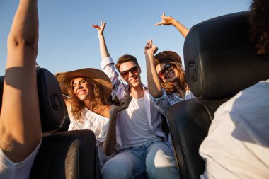 Şapka büyüleyici genç esmer kadın genç adam siyah Cabriolet ile oturma ve onların elele