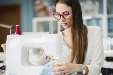 Beyaz gömlek giymiş bir akıllı görünümlü oldukça brunet ile elektrikli dikiş makinesi dikiş kadındır. Moda, terziler atölye.