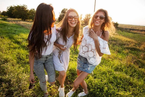 美丽的年轻妇女戴着太阳镜穿着漂亮的衣服站在田野里, 在一个阳光明媚的日子里微笑着. — 图库照片
