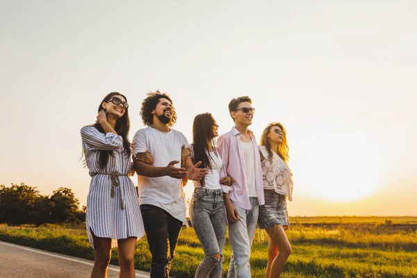 Giovani alla moda due ragazzi e tre ragazze camminano su una strada di campagna in una giornata di sole — Foto Stock