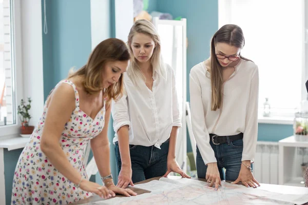 Tre pene damer som ser smarte ut peker på en cut-out. Mote, skredderforretning . – stockfoto