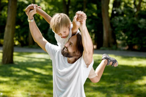 O pai está a brincar com o filho. O pai levantou o filho no ombro direito e sorriu. O rapaz está espantado. . — Fotografia de Stock
