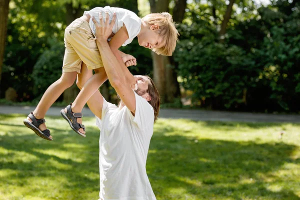 Giornata estiva soleggiata. Padre allegro sollevò il figlio sopra di sé e lo solleticò . — Foto Stock