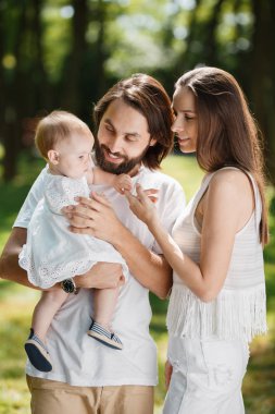 Beyaz giysiler giymiş güzel anne küçük sevimli kızları parkta bir yerde silah tutuyorsun