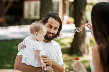 Esmer kadın sabun köpüğü açık yapma. Baba ile kızı ona dikkatle baktığını ve gülümseyen kollarında.