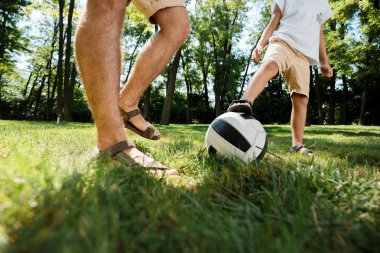 Yakışıklı baba ve küçük oğlu Beyaz tişörtler giymiş futbol sıcak bir günde bir bahçede oynayan.