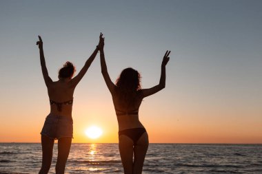 Mayo iki ince esmer kız ellerini denize yakın günbatımı üzerinde dur