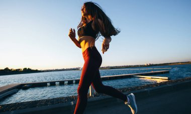 Sunset Bulvarında göl yolda spor kıyafetlerini giymiş uzun kahverengi saçlı güzel genç kız çalışır