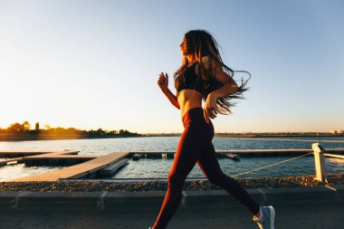 Sunset Bulvarında göl yolda spor kıyafetlerini giymiş uzun kahverengi saçlı güzel genç kız çalışır