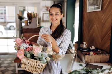Çizgili bir elbise giymiş güzel esmer kız pastel renkler n sepeti taze çiçek buketi Çiçekçi Dükkanı tutar.