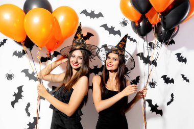 Witchs şapka büyüleyici genç kadınlarda iki siyah yarasalar ve örümcekler beyaz bir arka plan üzerinde siyah ve turuncu balon tutun