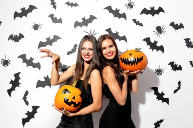 İki güzel esmer kadın siyah elbiseler jack-o-fener yarasalar ve örümcekler beyaz bir arka plan üzerinde eğlenin