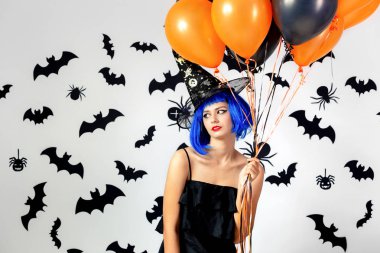 Balonlarda bir mavi peruk ve witchs şapka siyah ve turuncu siyah yarasalar ve örümcekler beyaz bir arka plan üzerinde genç kadın