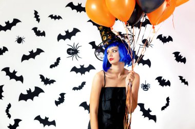 Balonlarda bir mavi peruk ve witchs şapka siyah ve turuncu siyah yarasalar ve örümcekler beyaz bir arka plan üzerinde genç kadın