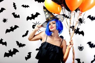 Balonlarda bir mavi peruk ve witchs şapka siyah ve turuncu siyah yarasalar ve örümcekler beyaz bir arka plan üzerinde genç kadın