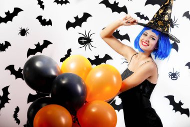 Young woman in a blue wig and witchs hat black and orange balloons on a white background with black bats and spiders clipart