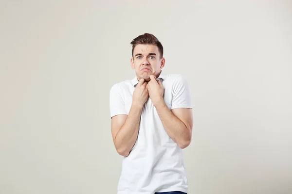 Surpreendido cara vestido com uma camiseta branca e jeans está em um fundo branco no estúdio — Fotografia de Stock