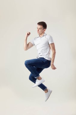Mutlu adam bir beyaz giyinmiş t-shirt ve jeans atlar stüdyoda beyaz bir arka plan üzerinde