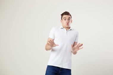 Ve kot pantolon olduğunu stüdyoda beyaz bir arka plan üzerinde beyaz bir t-shirt giymiş adam merak