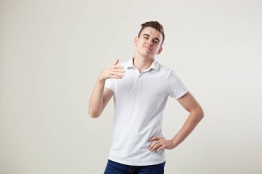 Indifferent  guy dressed in a white t-shirt and jeans is on a white background in the studio clipart