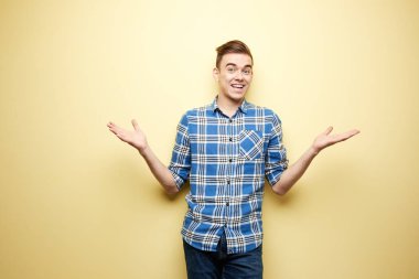 Bir ekose gömlek ve kot standları stüdyoda sarı duvar yanında neşeli adam giymiş