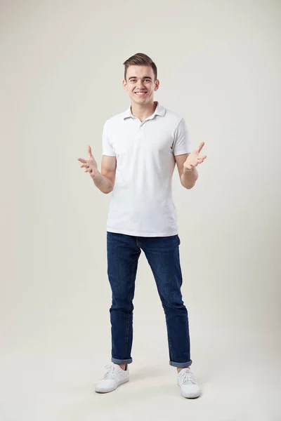 Cara alegre vestido com uma camiseta branca e jeans stand no estúdio em um fundo branco — Fotografia de Stock