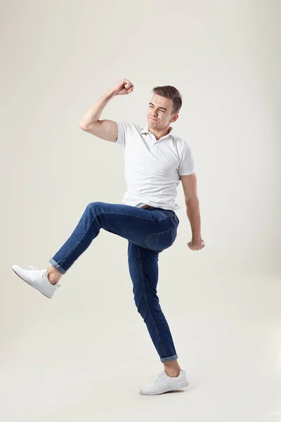 Extático cheio de energia cara vestido com uma camiseta branca e jeans se move em um fundo branco no estúdio — Fotografia de Stock