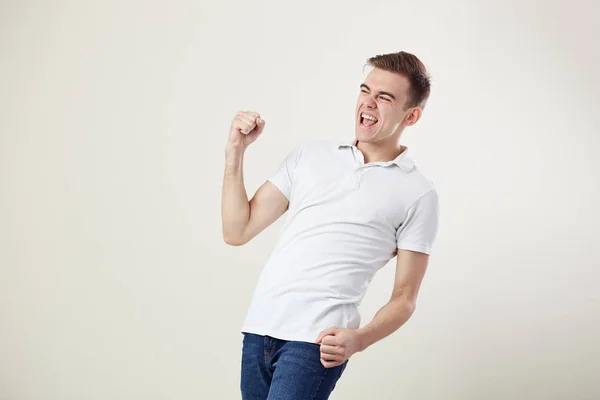 Extatisk full av energi kille klädd i en vit t-shirt och jeans ropar i studion på en vit bakgrund — Stockfoto