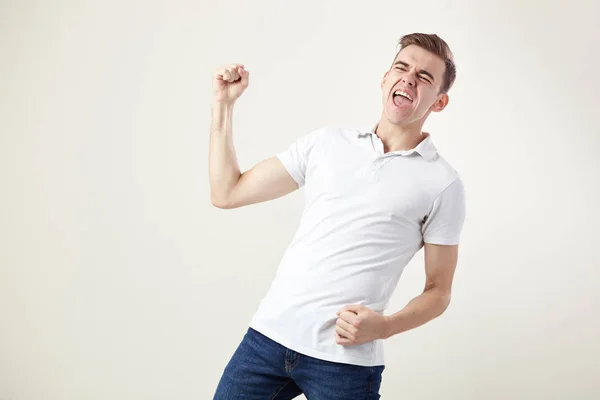 Ecstatic full of energy  guy dressed in a white t-shirt and jeans shouts in the studio on a white background — Stock Photo, Image