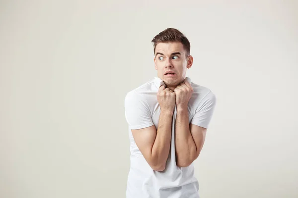 Cara assustado vestido com uma camiseta branca e jeans está em um fundo branco no estúdio — Fotografia de Stock