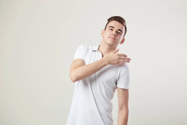 Tipo indiferente vestido con una camiseta blanca y pantalones vaqueros está sobre un fondo blanco en el estudio —  Fotos de Stock