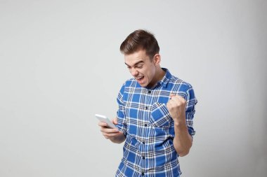 Kendinden geçmiş bir ekose gömlek giymiş enerji adam dolu cep telefonu elinde beyaz bir arka plan stüdyo tutar