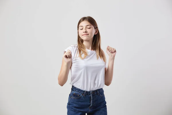 Kalm en gelukkig meisje gekleed in een wit t-shirt en jeans is op een witte achtergrond in de studio — Stockfoto