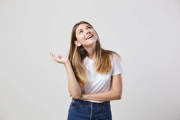 Soñar chica vestida con una camiseta blanca y jeans es sobre un fondo blanco en el estudio — Foto de Stock