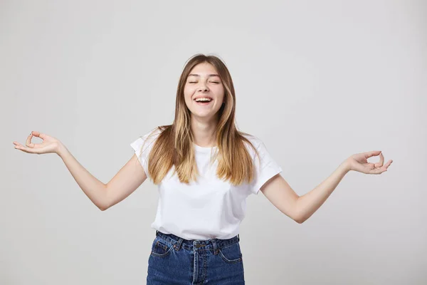 Vrolijk en rustig meisje gekleed in een wit t-shirt en jeans is op een witte achtergrond in de studio — Stockfoto