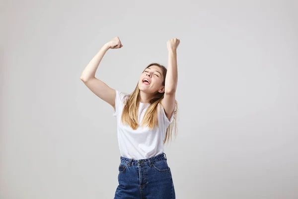 Vrolijk en rustig meisje gekleed in een wit t-shirt en jeans heeft leuk op een witte achtergrond in de studio — Stockfoto