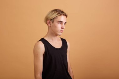 Siyah bir tişört ve pantolon bej renkli arka plan üzerinde stüdyoda poz giyinmiş genç Sıska sarışın adam
