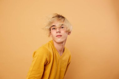 Sarı kazak giymiş genç sarışın adam stüdyo bej renkli arka plan üzerinde poz