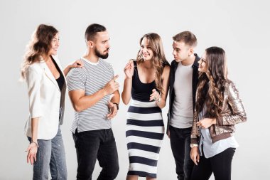 Kızlar ve çocuklar moda rahat kıyafetler içinde şirket konuşmak stüdyoda beyaz bir arka plan üzerinde