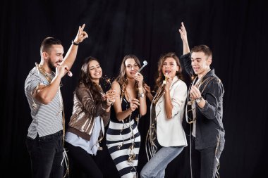 Parti zamanı. Casual Modern giyimleri arkadaş şirket stüdyoda siyah bir zemin üzerine şeritler ve borular ve havai fişekleri ile eğlenceli yaşıyorsanız