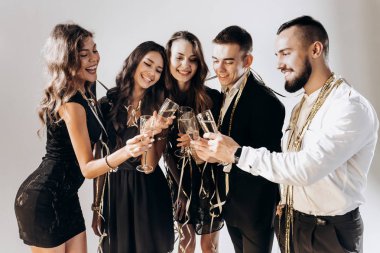 Güzel genç kızlar ve erkekler şık şık giysileriyle gülümseme birlikte ve kodes bardak şampanya studio lezzetli beyaz bir arka plan ile giyinmiş. Parti zamanı