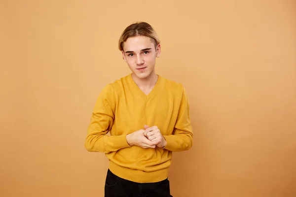 Молодий блондинка, одягнений в жовтий светр, позує в студії на бежевому фоні — стокове фото