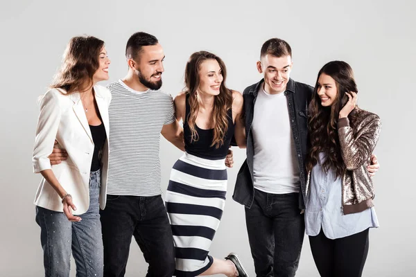 Empresa de meninas e caras em roupas casuais na moda falar em um fundo branco no estúdio — Fotografia de Stock