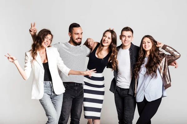 Εταιρεία νέοι ντυμένοι με κομψά casual ρούχα χαμόγελο και να διασκεδάσουμε όλοι μαζί σε ένα λευκό φόντο στο στούντιο — Φωτογραφία Αρχείου