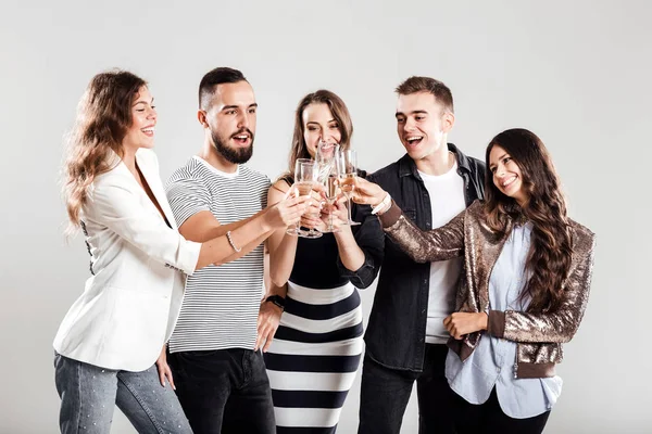 Kızlar ve şık rahat kıyafetler giymiş çocuklar yan yana ve şampanya ile gözlük tıklatması. Parti zamanı