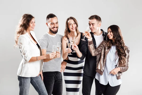 Kızlar ve şık rahat kıyafetler giymiş çocuklar yan yana ve şampanya ile gözlük tıklatması. Parti zamanı