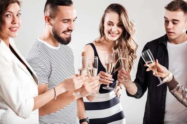 Kızlar ve şık rahat kıyafetler giymiş çocuklar yan yana ve şampanya ile gözlük tıklatması. Parti zamanı