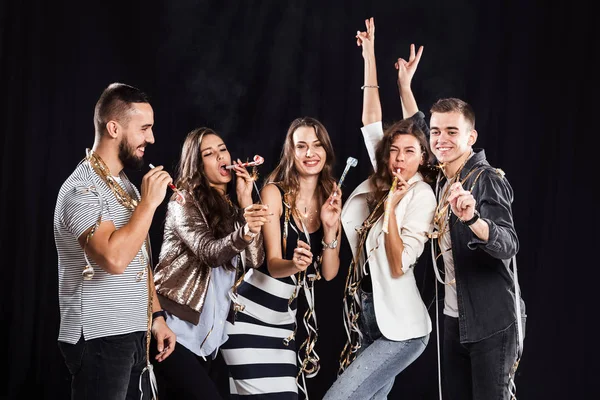 Parti zamanı. Casual Modern giyimleri arkadaş şirket sevinirler ve stüdyoda siyah bir zemin üzerine iyi eğlenceler