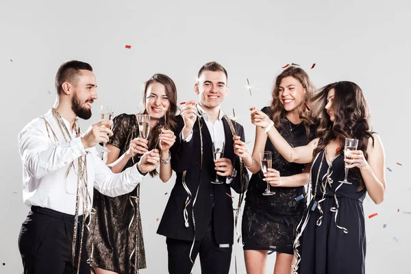 Společnost dívky a kluci v stylové elegantní oblečení bavte se společně držení sklenice šampaňského a jiskří v rukou na bílém pozadí cukrárnu a okolí. Mejdan — Stock fotografie