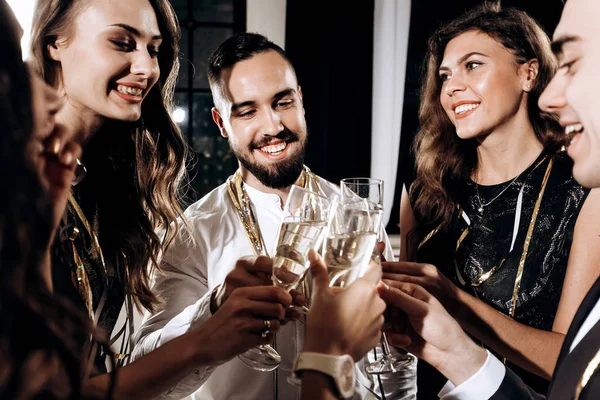 Gezelschap van vrienden gekleed in stijlvolle elegante kleding stand samen en clink bril met champagne. Tijd van de partij — Stockfoto